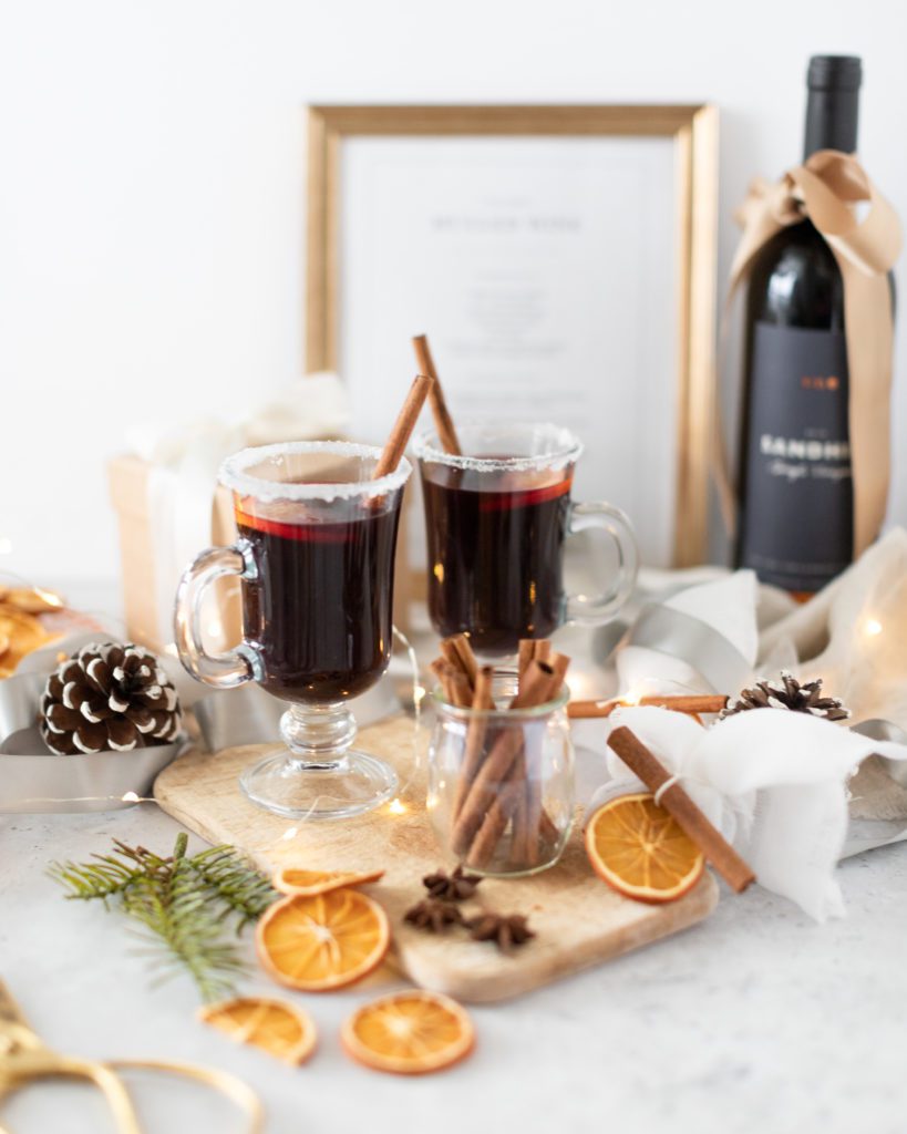Red mulled wine in glass mugs with dried oranges and cinnamon sticks