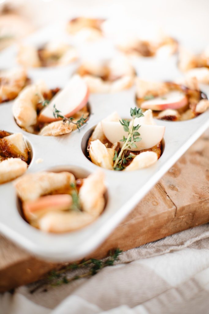 Baked brie bites in muffin tin with apple slices and thyme