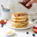 Angel cakes pancakes stack with hand pouring syrup