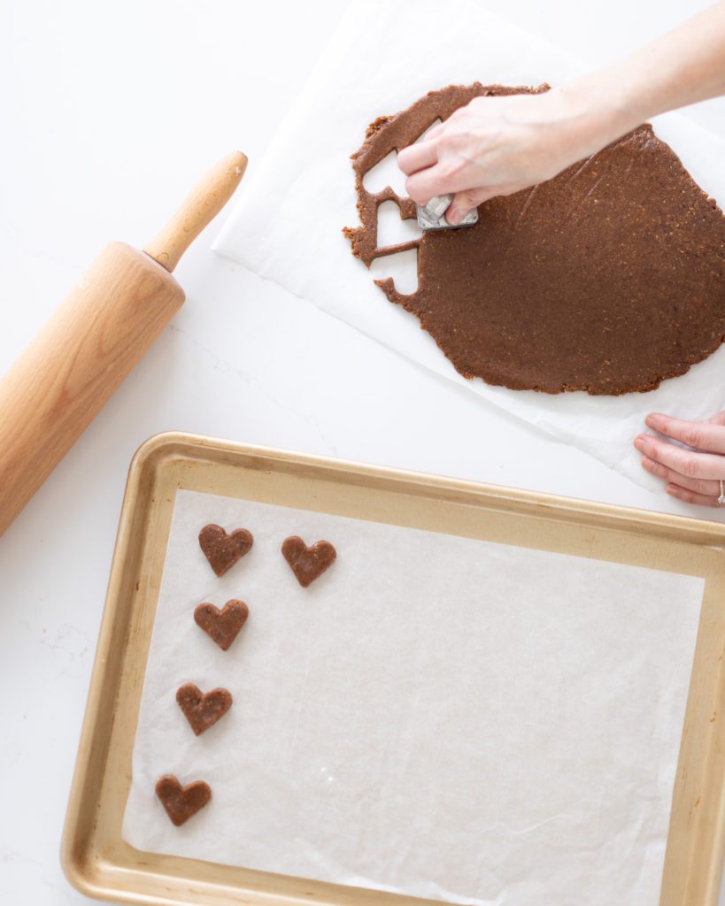 Making Chocolate Covered Date Turtles on white surface with rolling pin