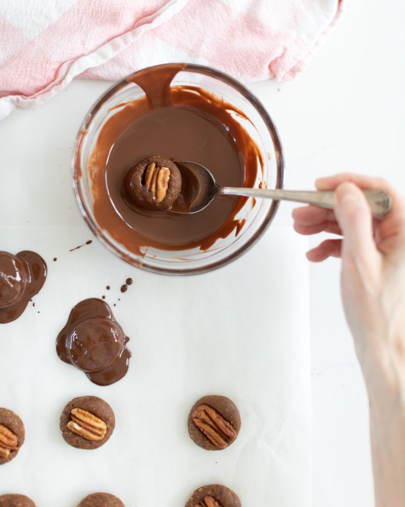 making Chocolate Covered Date Turtles by dipping in melted chocolate