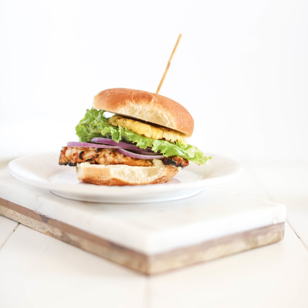 Teriyaki Chicken Burgers on a plate with pineapple, lettuce and onion