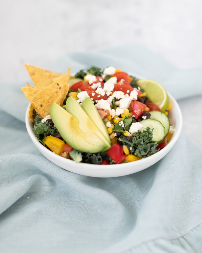 kale southwest salad small bowl with tortilla chips, avocado, and diced vegetables