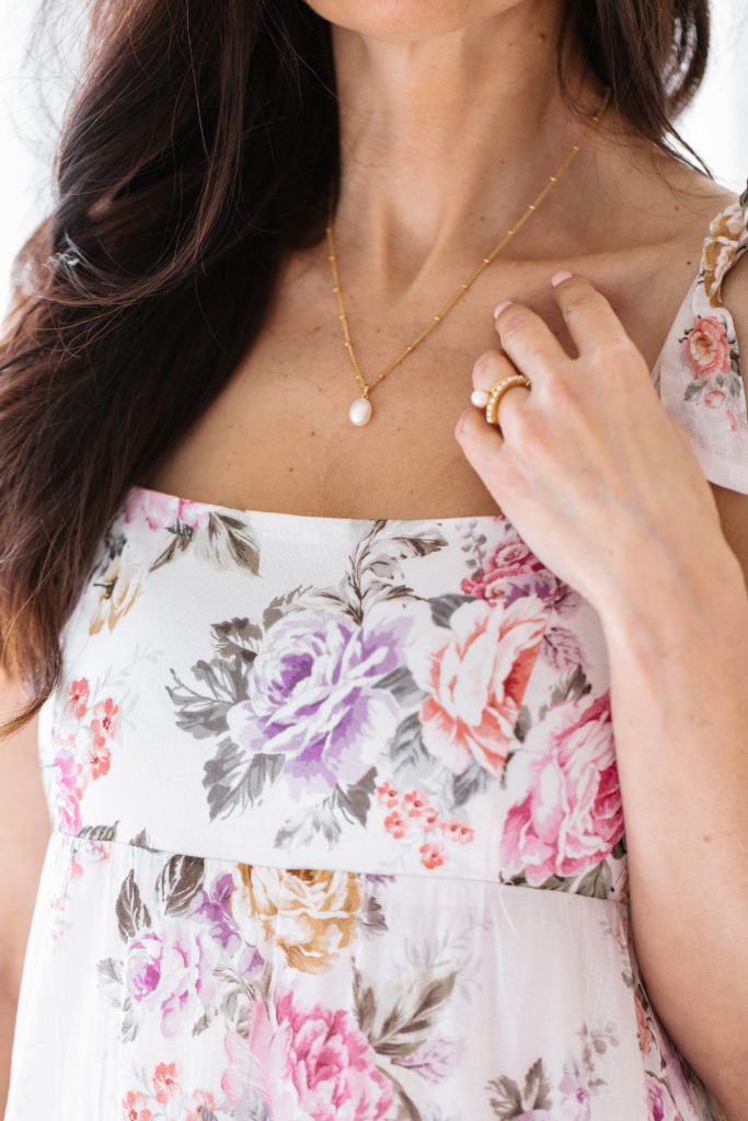 Tori wearing so pretty cara cotter pearl necklace in a floral dress