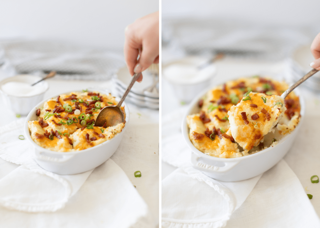 Hand scooping out Loaded Mashed Potatoes win a baking dish with bacon, cheese and green onions on top