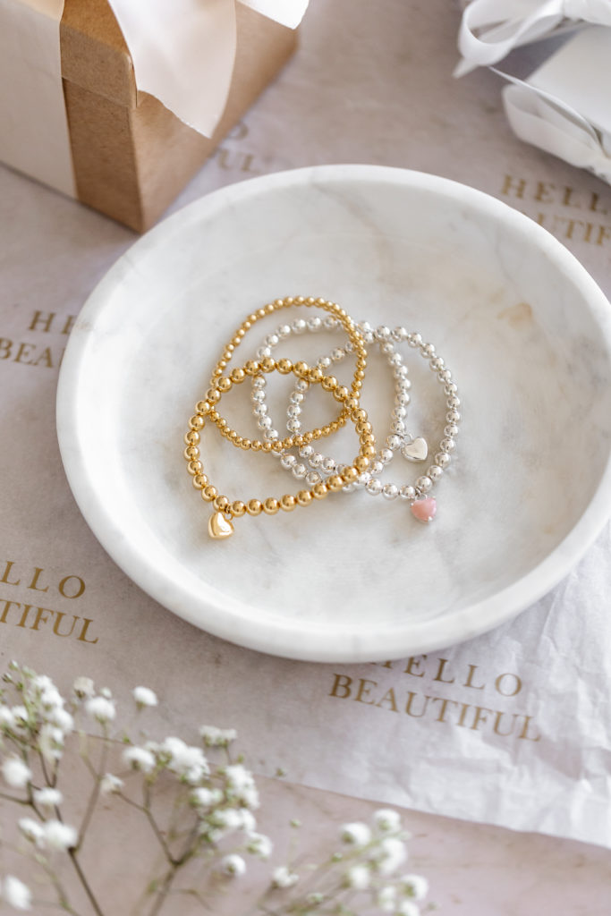 gold and silver stackable bracelets in a dish