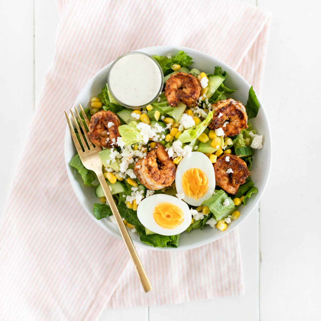 Fraiche Table Cajun Shrimp Cobb Salad in one bowl with a hard boiled egg and shrimp on top