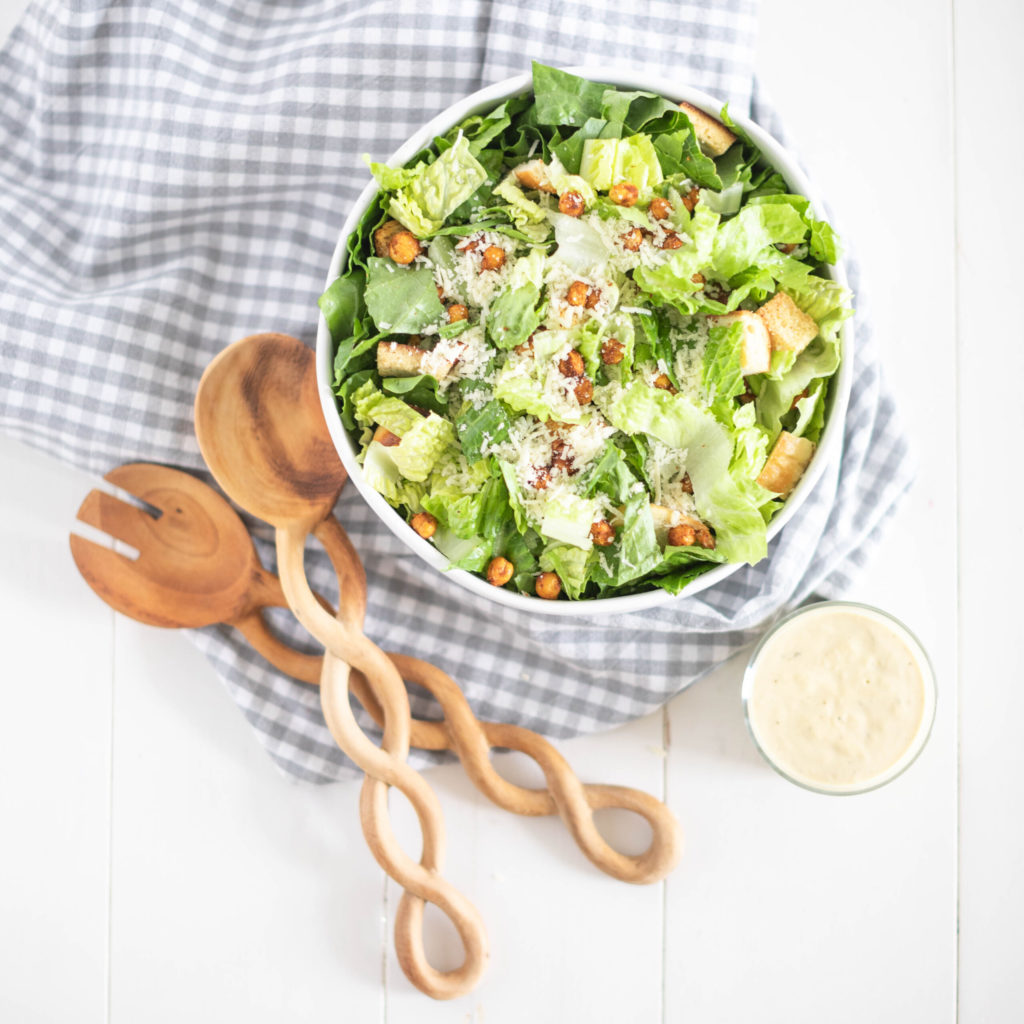 Fraiche Table Tahini Caesar salad in one bowl with a side of salad dressing and spoons