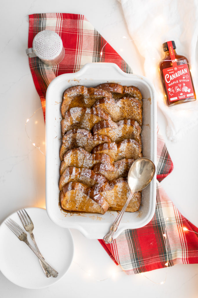 Baked Eggnog French Toast in a casserole dish with maple syrup
