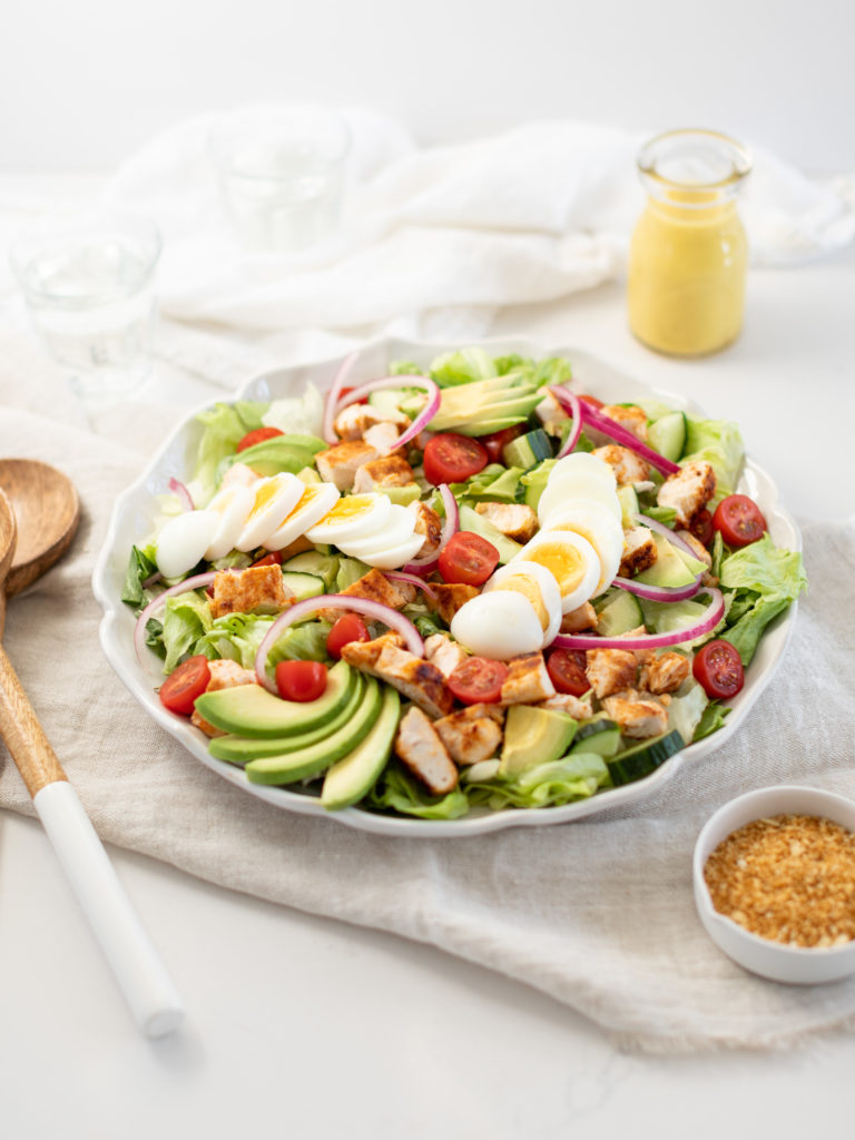 Honey Mustard Chicken Salad in a bowl topped with tomato, avocado, and hard boiled eggs.