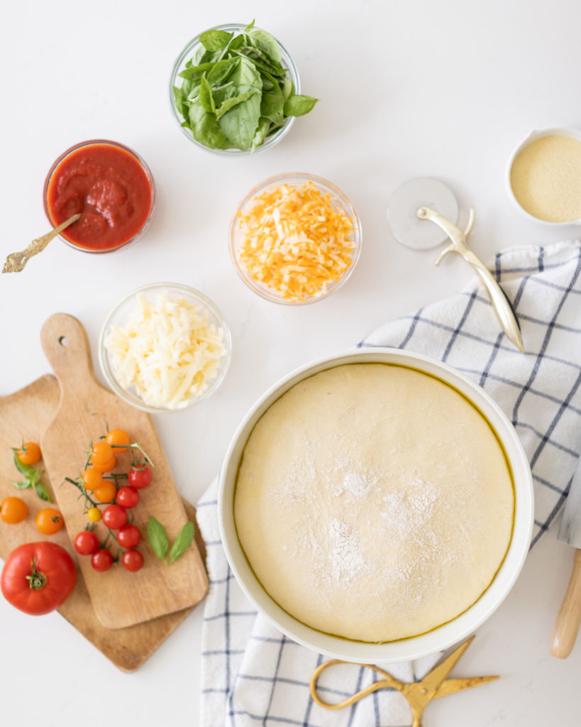 ingredients to make Homemade Pizza Pockets in bowls including the dough, tomato sauce, cheese and basil