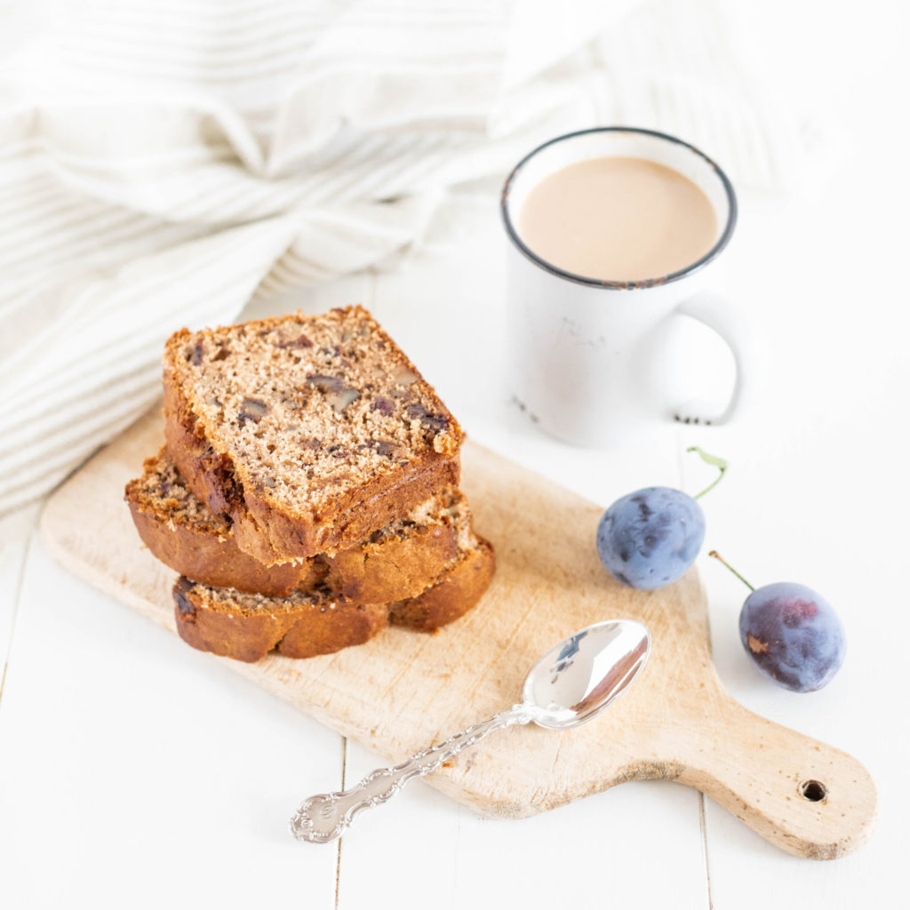 fruit and nut loaf sliced on a wood board with a cup of coffee