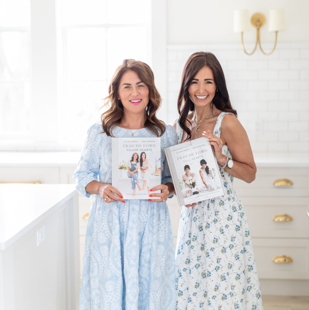 Tori and Jill smiling while holding both of their cookbooks