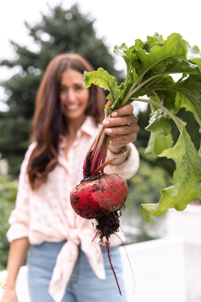 Tori holding beets in her vegetable garden