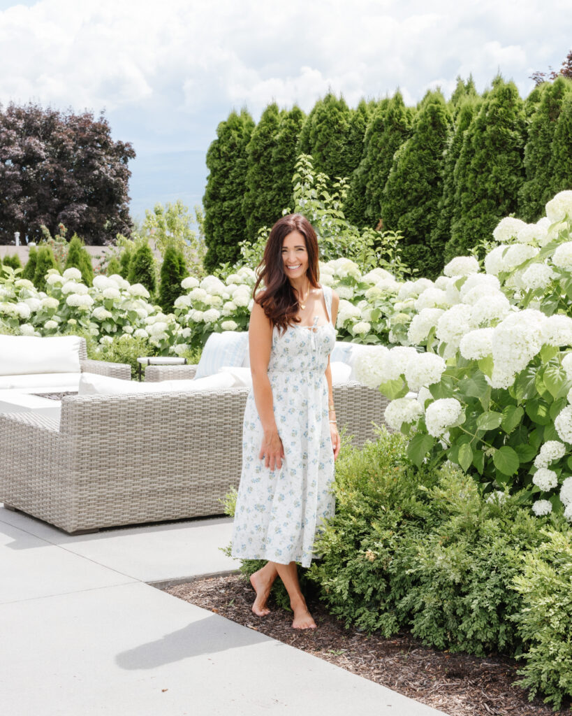 Tori Wesszer standing in a garden full of white hydrangeas