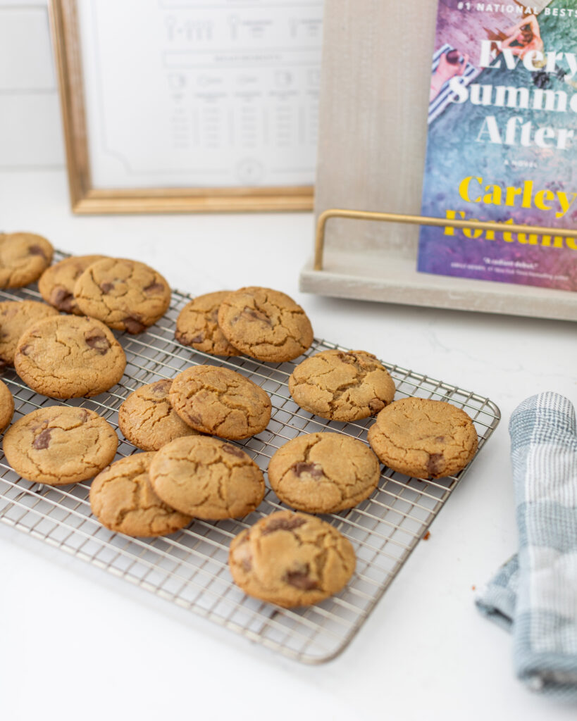 Moose Track Cookies on a cooling rack next to the July book of the month for the Fraîche Bookie Club "Every Summer After" by Carley Fortune