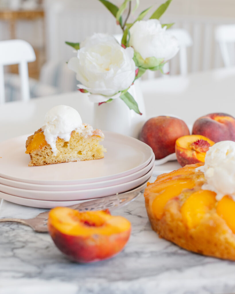 Peach Upside Down Cake sliced on a plate with a scoop of vanilla ice cream