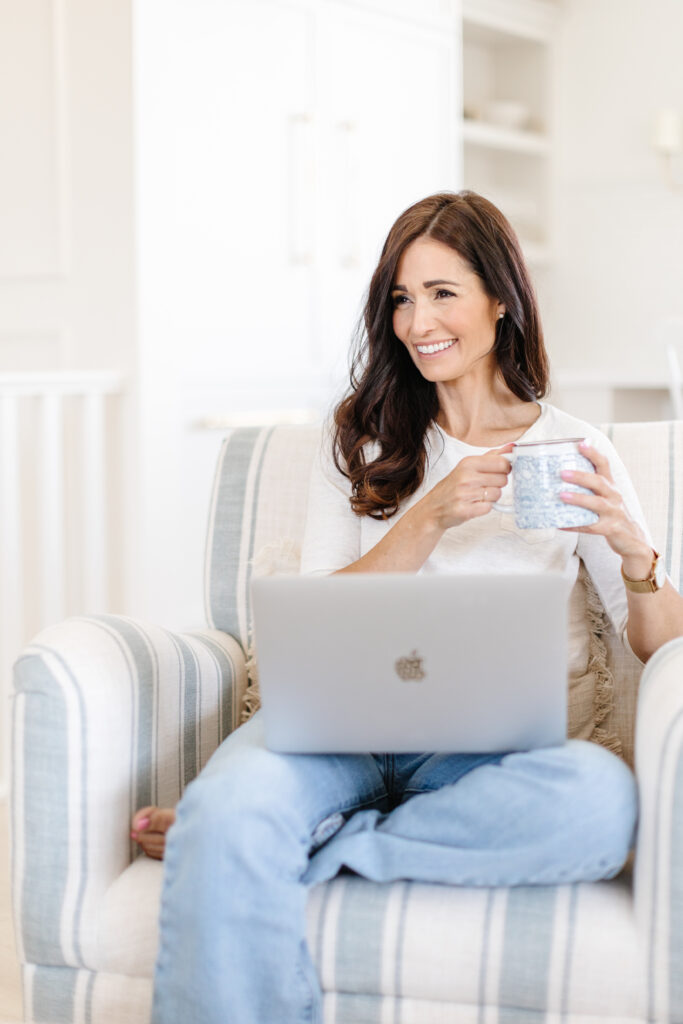 laptop open on women's lap holding a cup of coffee