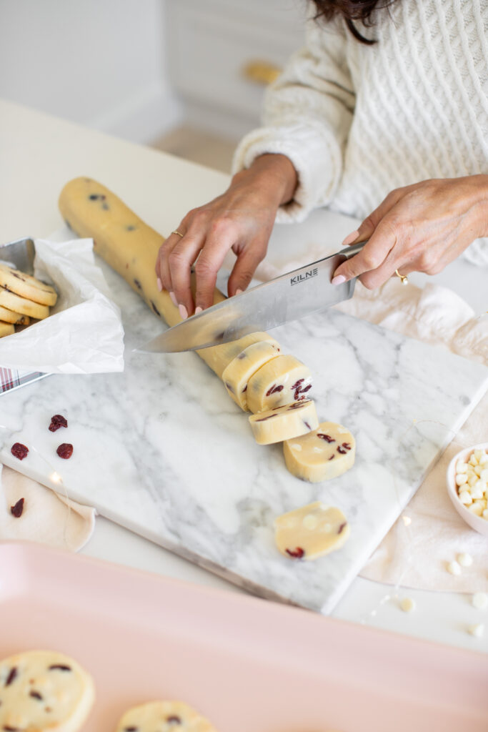 women slicing  Cranberry White Chocolate Slice & Bake Cookies on a cutting board