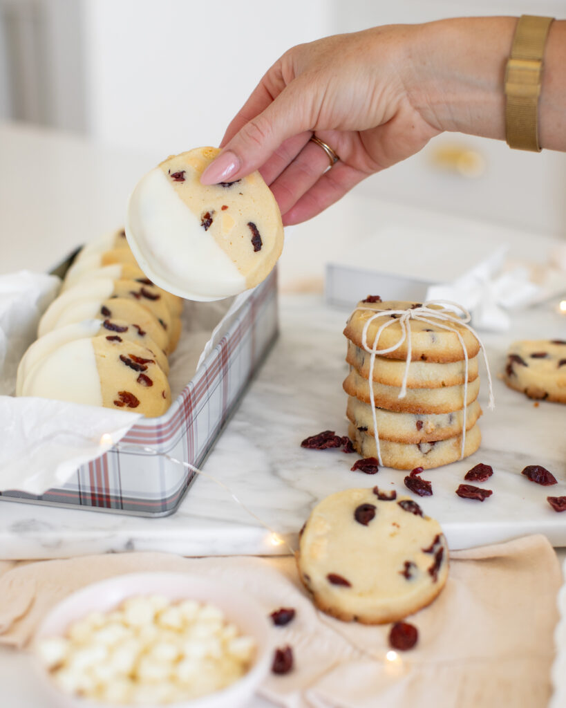 hand grabbing a Cranberry White Chocolate Slice & Bake Cookie our of a cookie tin