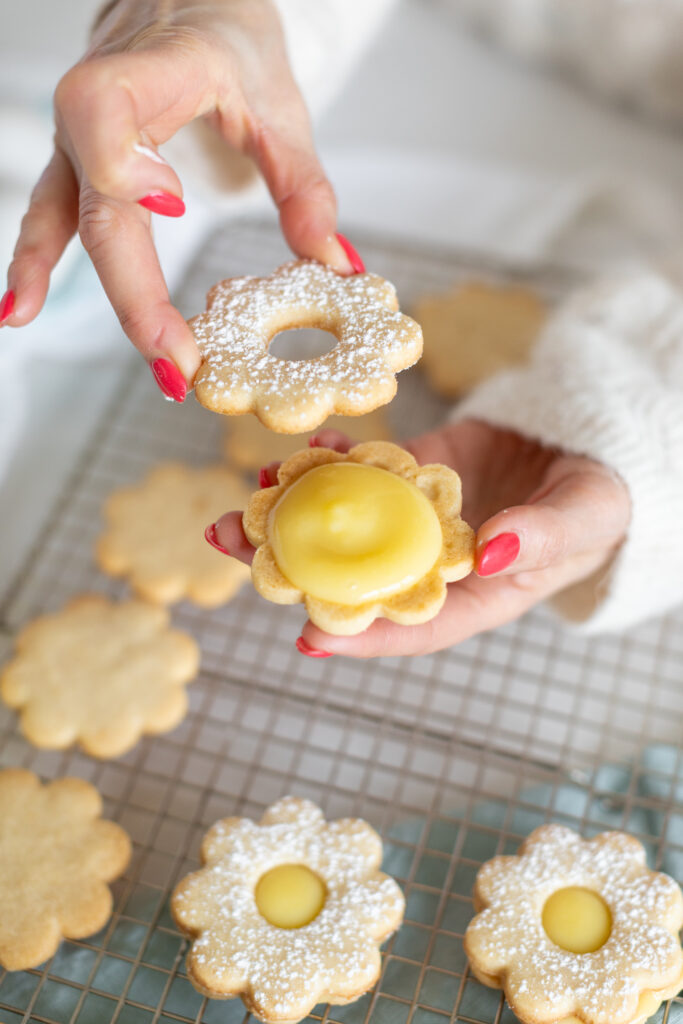 a hand sandwiching a Lemon Cut-Out Cookies 