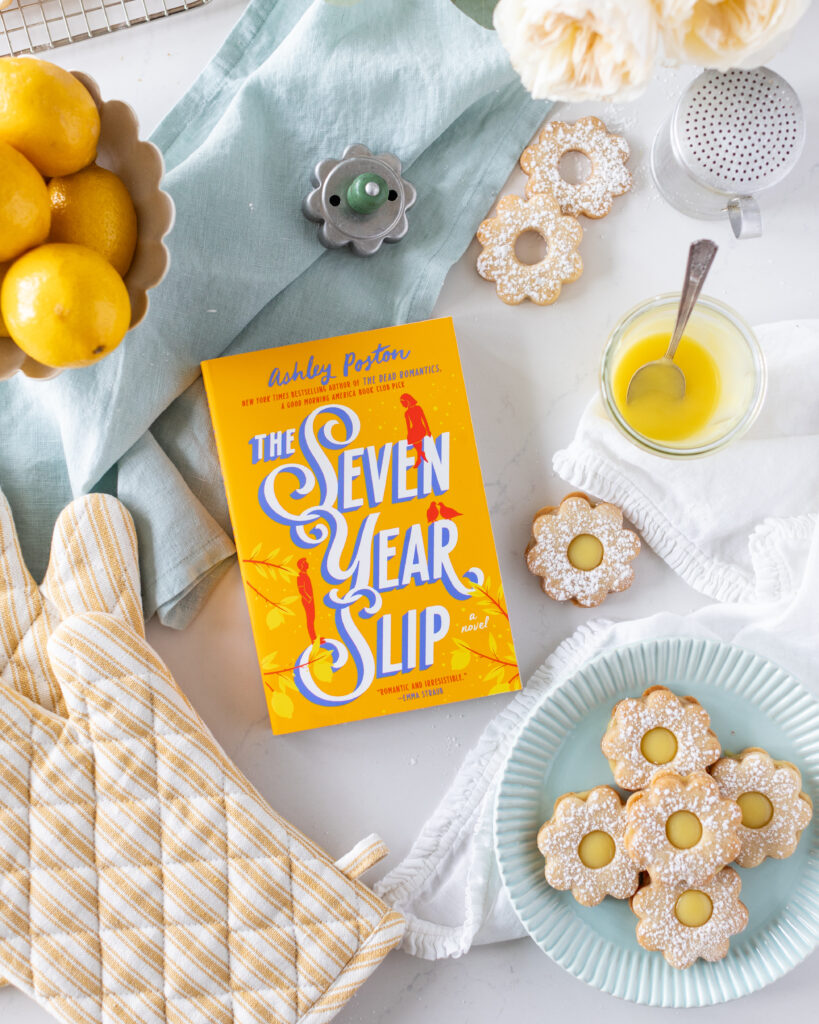 The book "The Seven Year Slip" By Ashley Poston, beside Lemon Cut-Out Cookies 