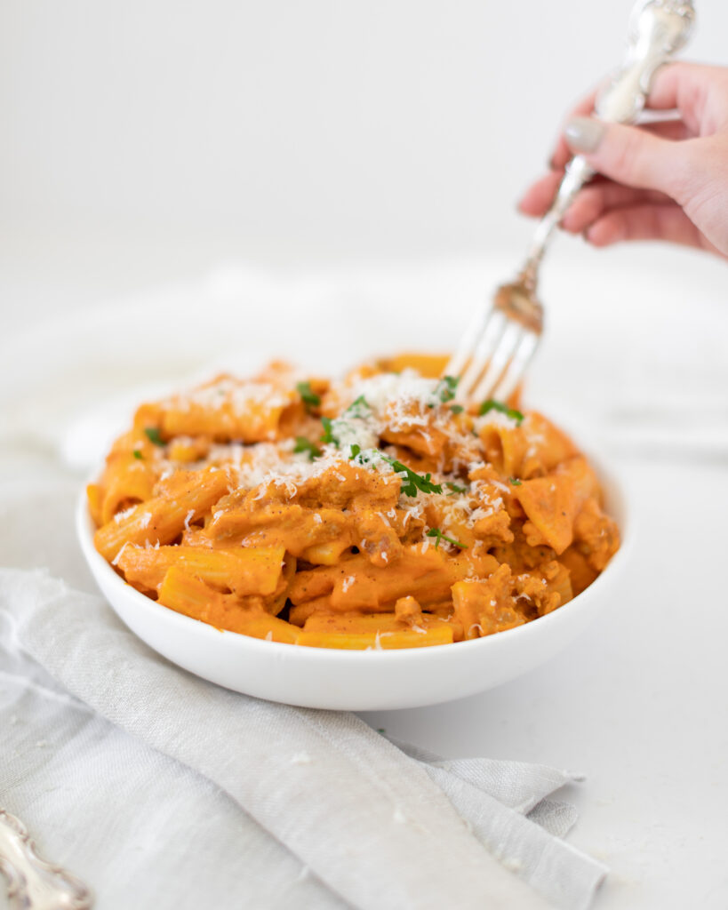 Hand scooping fork into bowl of Date Night Rigatoni