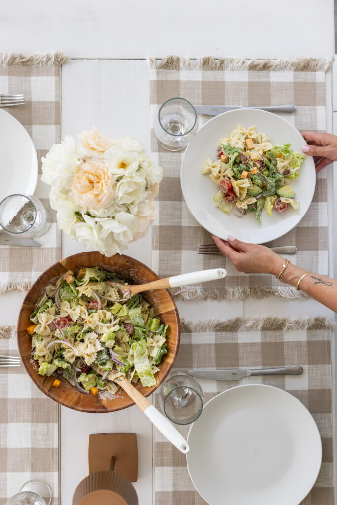 Table setting with flowers and plates with BLT Pasta Salad