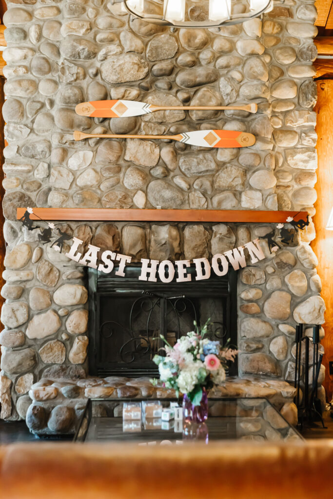 "Last Hoedown" sign and décor set up at the cabin over rock fireplace for a themed Jasper bachelorette weekend