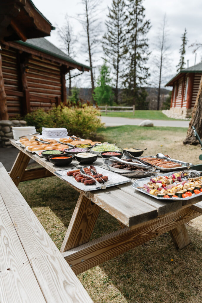 Outdoor picnic table dinner setup with hotdogs during a mountain bachelorette weekend in Jasper.