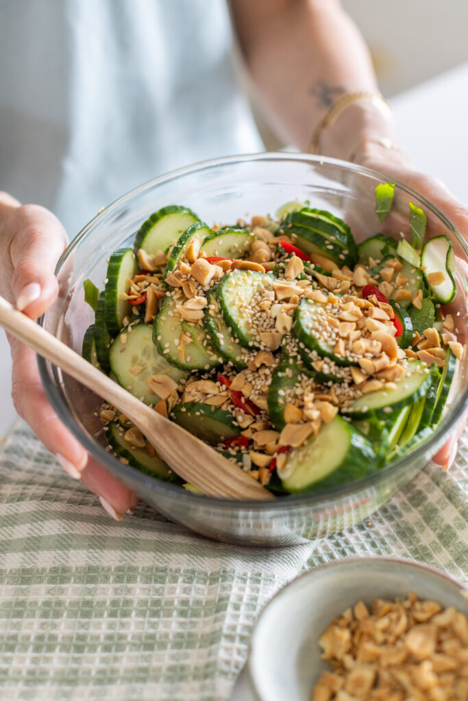 Overhead view of spicy cucumber salad garnished with fresh mint and crushed peanuts
