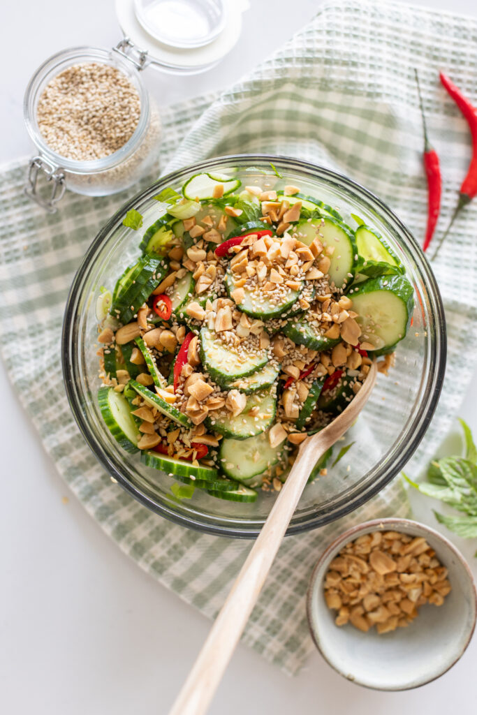 Overhead view of spicy cucumber salad garnished with fresh mint and crushed peanuts