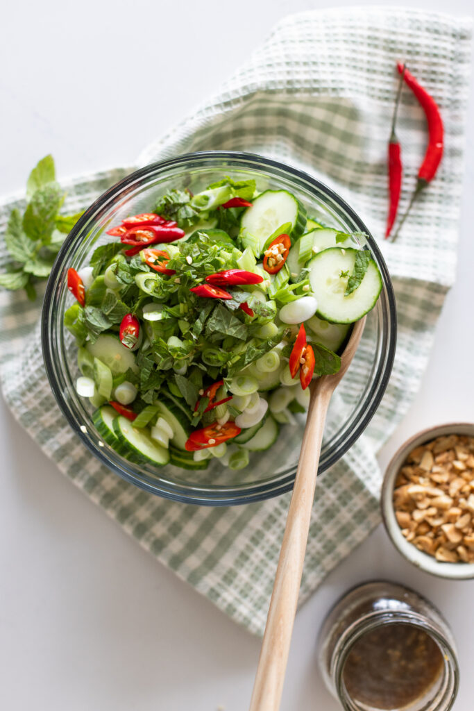 Overhead view of spicy cucumber salad garnished with fresh mint and thai chilis
