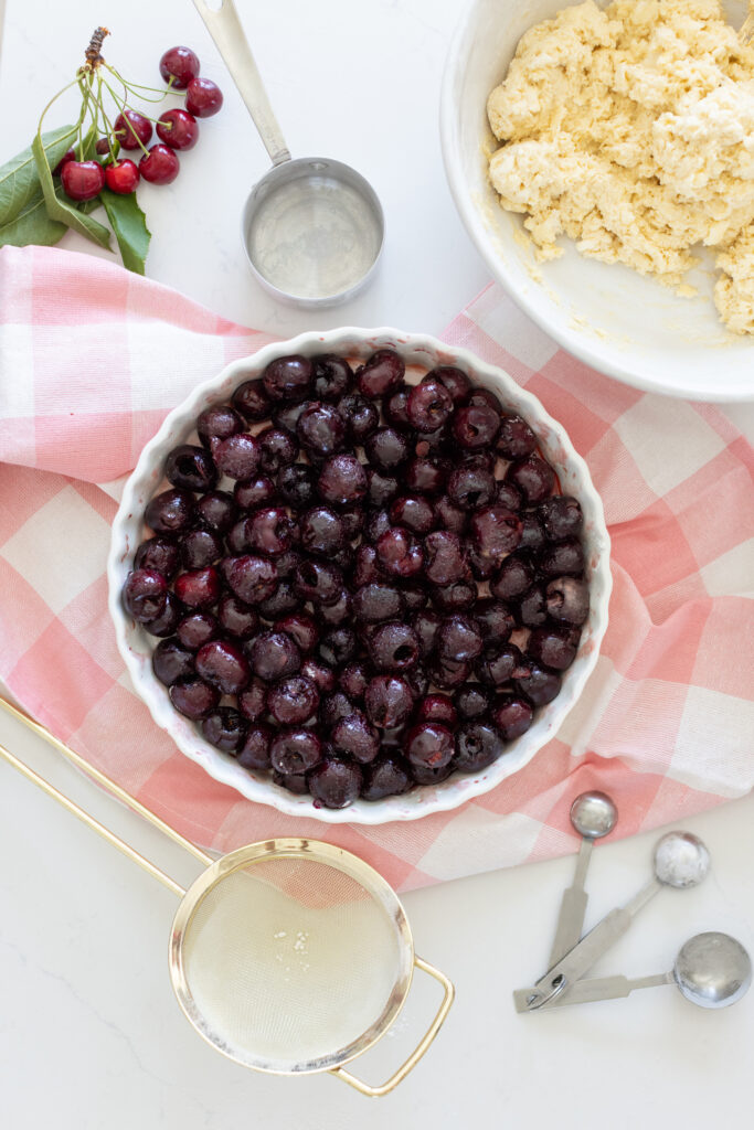 Unbaked classic cherry cobbler in a baking dish, with red cherry filling