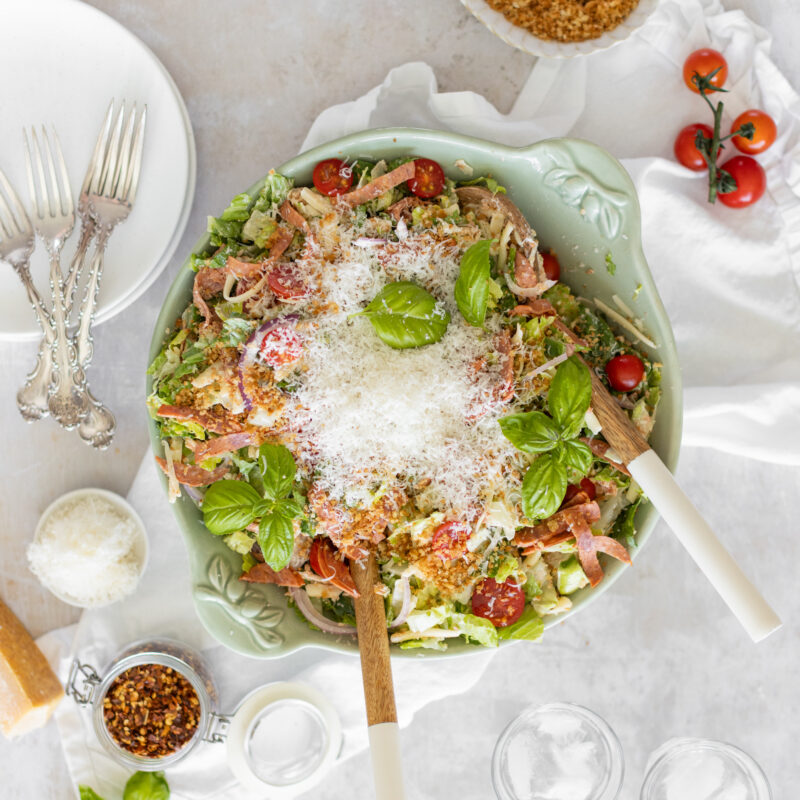Overhead shot of Pizza Ranch Salad in a large bowl, topped with pepperoni, and shredded cheese.