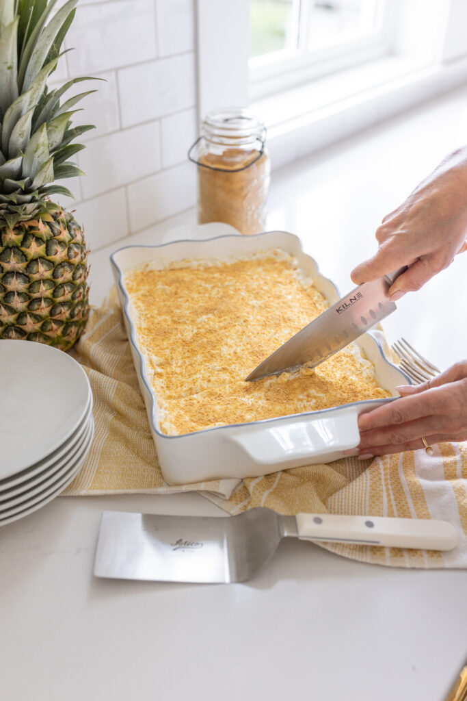 knife cutting Pineapple Delight in a 13×9 baking dish