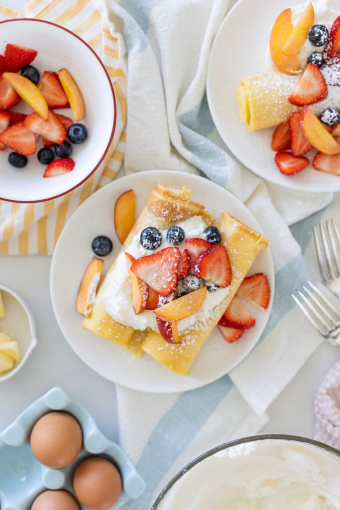 Sheet pan crepes topped with fresh strawberries, blueberries, and whipped cream, served on a white plate for an easy breakfast.